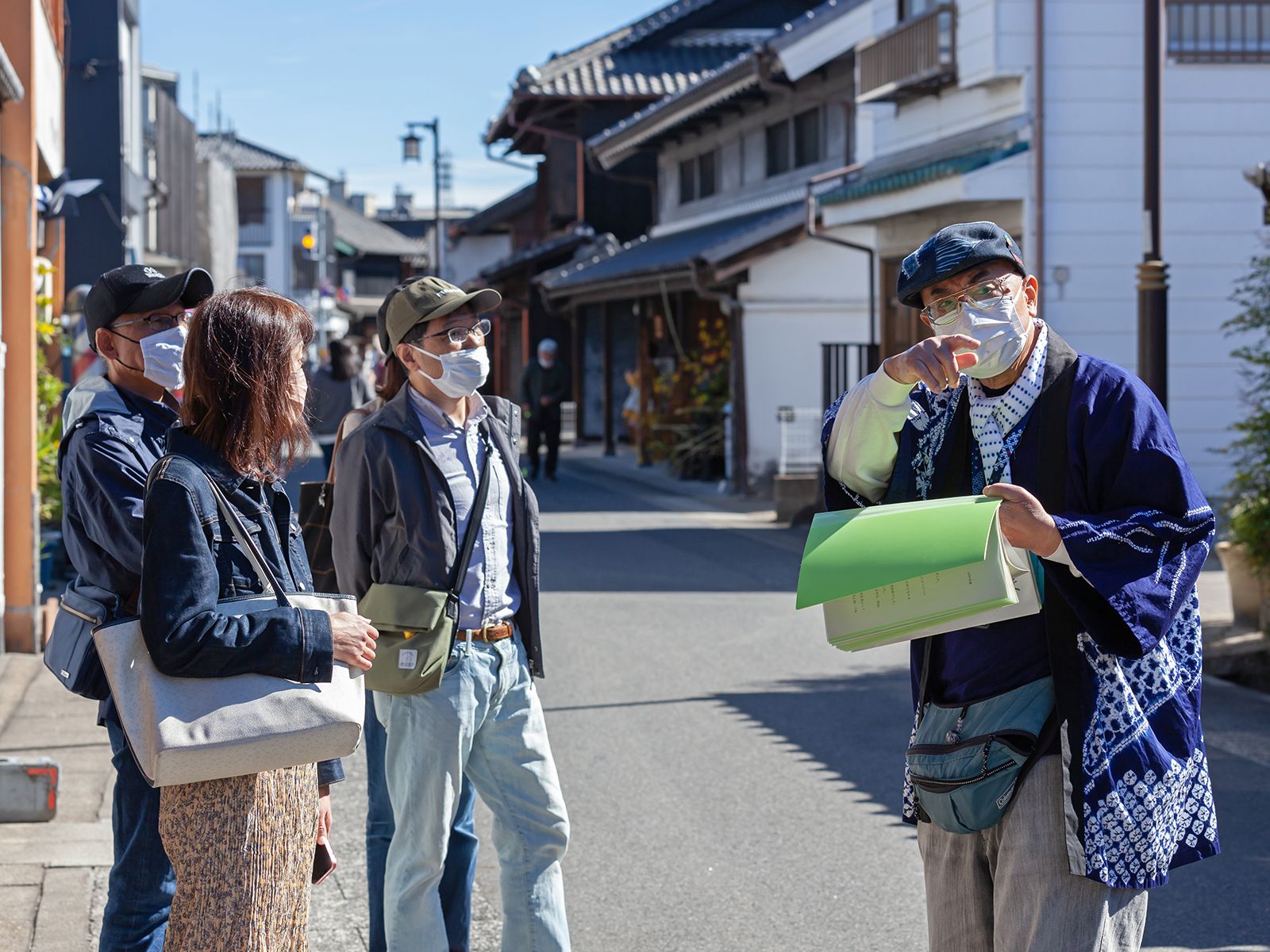 A guide in a happi coat explaining the streetscape along the Tokaido to visitors